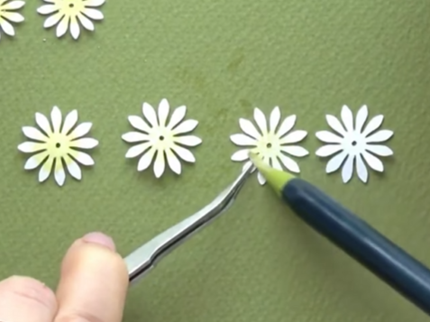Adding light green color to the center of small white paper flowers with a brush pen