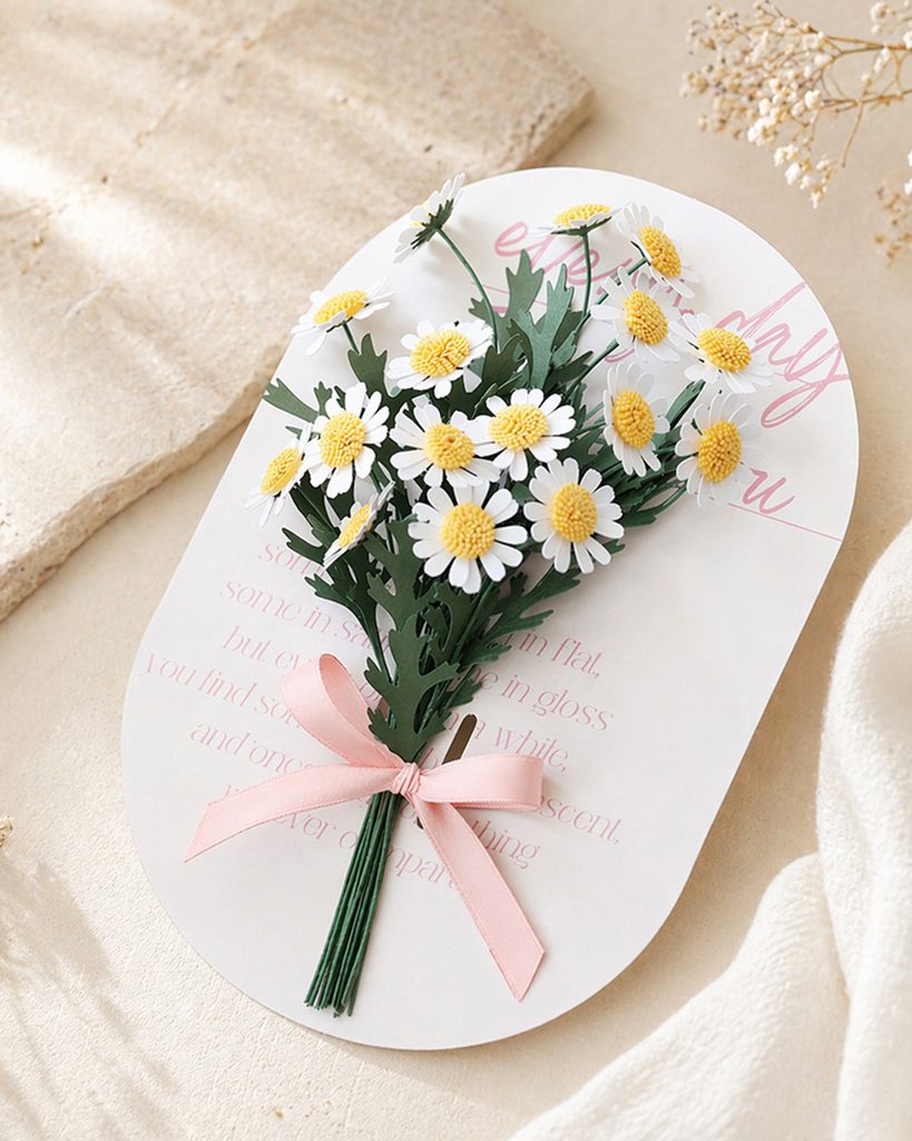 Mini daisy paper flower bouquet tied with a pink satin ribbon on a white message card