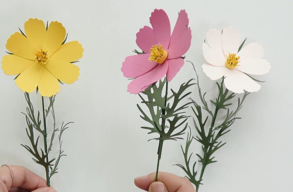 Finished yellow, pink, and white cosmos paper flowers with detailed green cardstock leaves and stems.