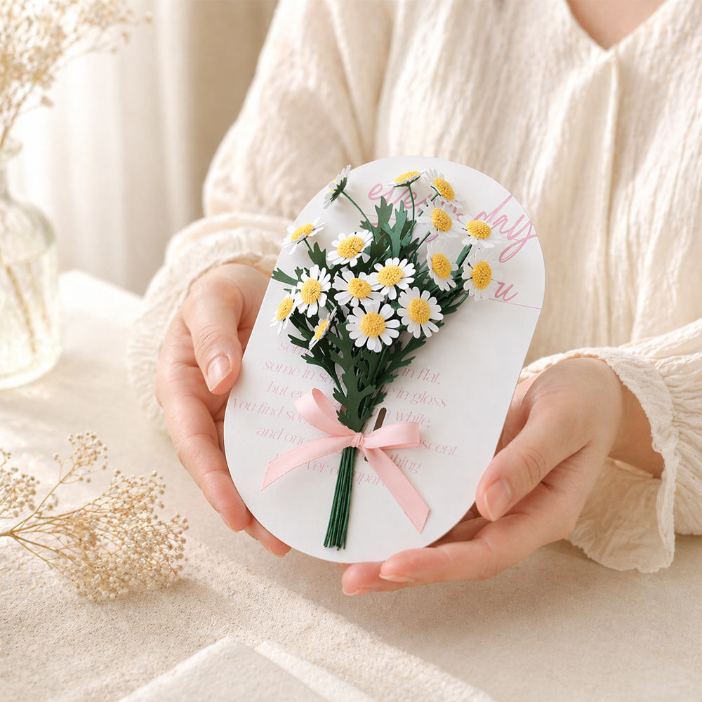 Mini daisy paper flower bouquet on a white message card tied with a pink satin ribbon