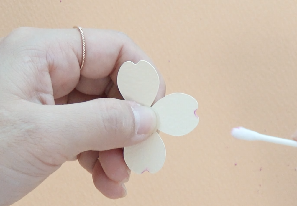 Applying pink pastel to the edges of ivory paper dogwood petals with a cotton swab