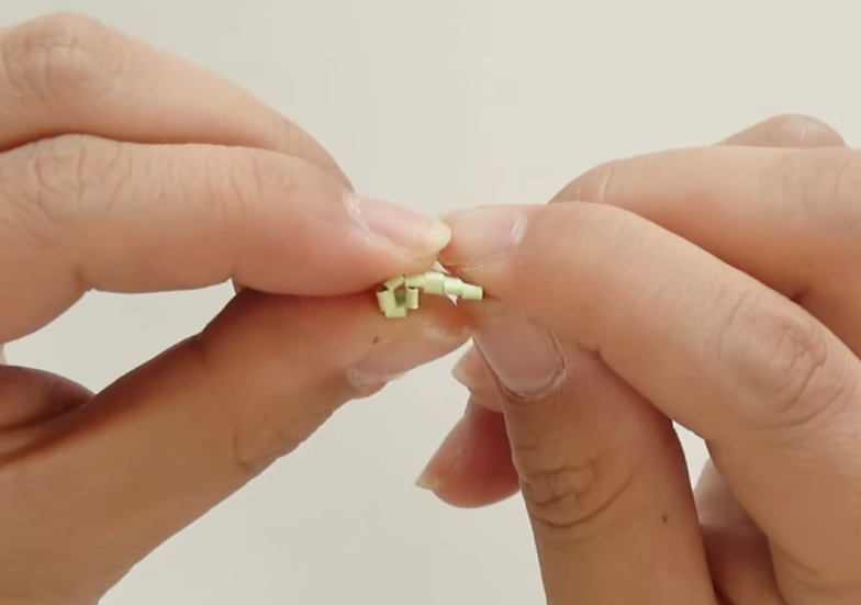 Shaping the folded light green paper stamen piece by hand for a dogwood paper flower