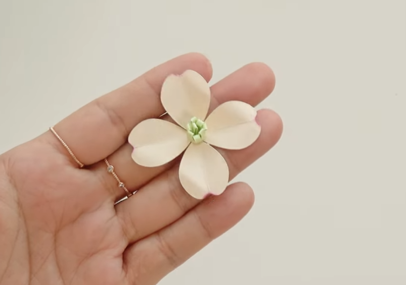 Finished ivory dogwood paper flower with four petals and a light green rolled paper stamen in the center