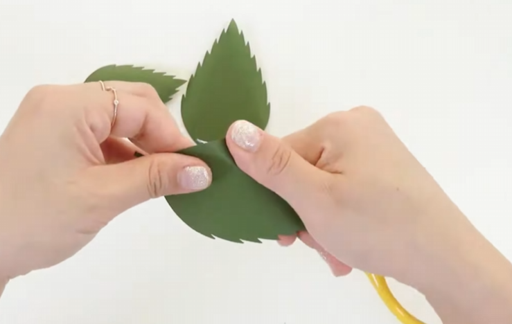 Shaping the edges of green cardstock sunflower leaves with scissors