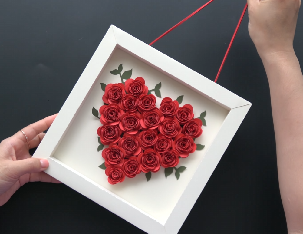Finished heart-shaped paper flower wall art with red rolled roses in a white frame