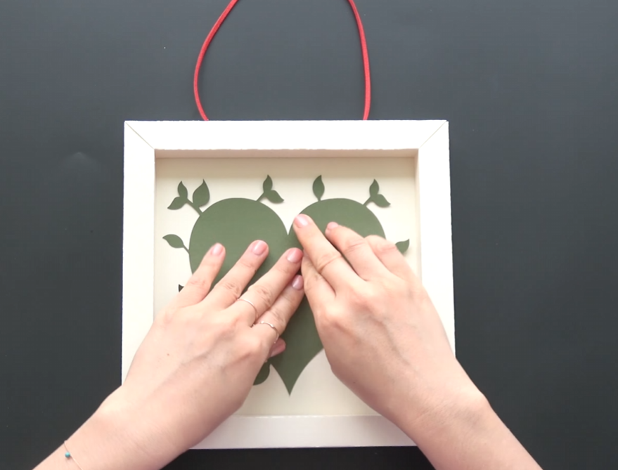 Attaching a green paper heart base inside the white frame
