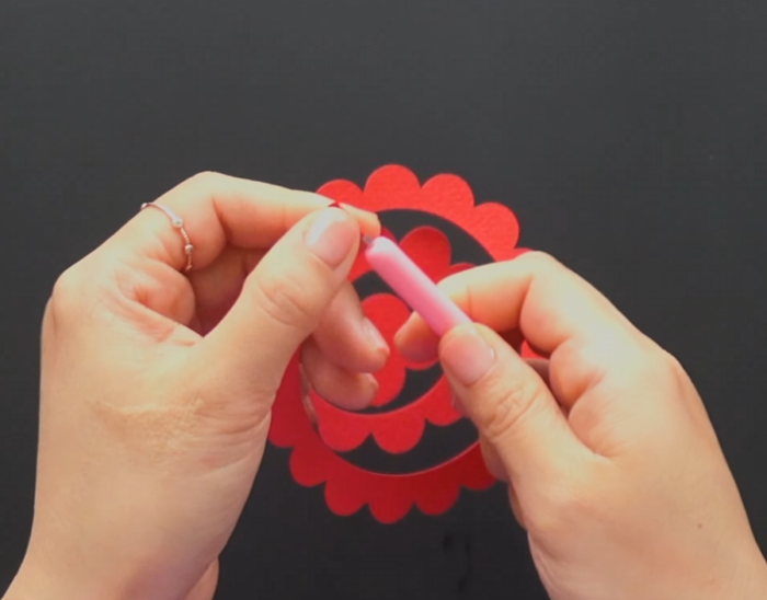 Rolling a red spiral paper flower pattern with a paper rolling tool