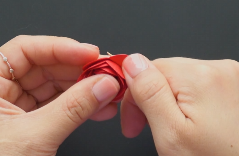 Curling the outer petals of a red rolled paper rose for a natural shape