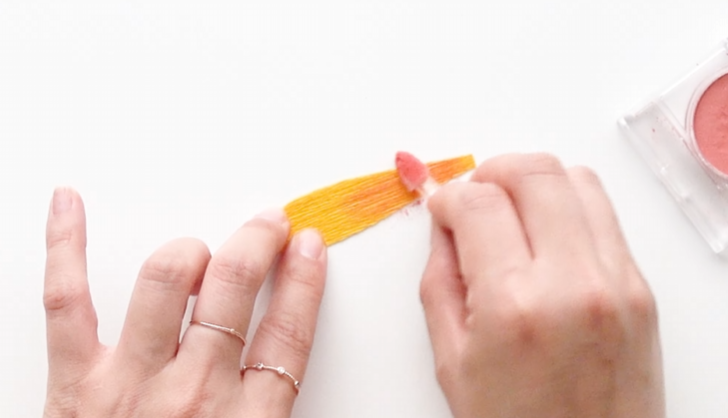 Adding peach shading powder to the base of a yellow sunflower petal