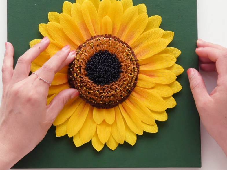 Attaching the textured flower center to complete the crepe paper sunflower wall art