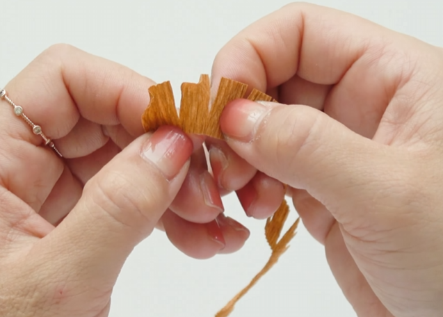 Twisting brown crepe paper fringe to create a wavy sunflower center texture
