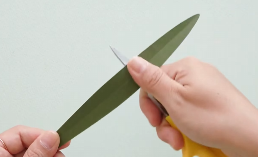 Curling a long green cardstock leaf with scissors for the paper daffodil