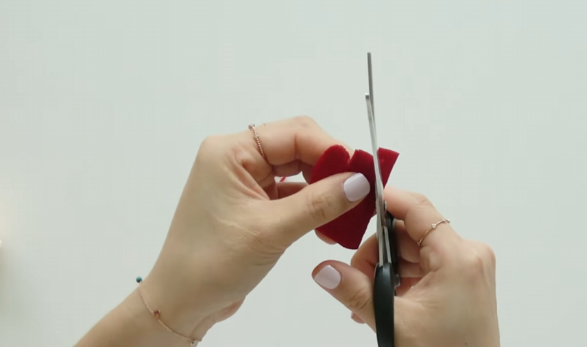 Rounding the top edges of red paper petals with scissors