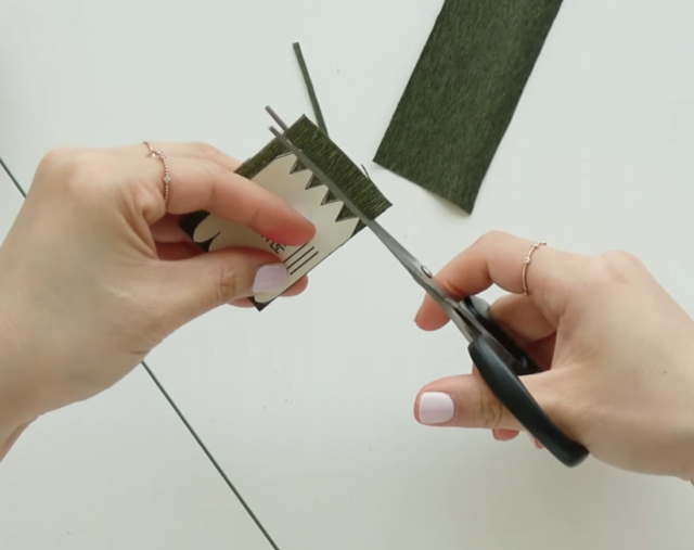 Cutting a green crepe paper sepal using the flower pattern