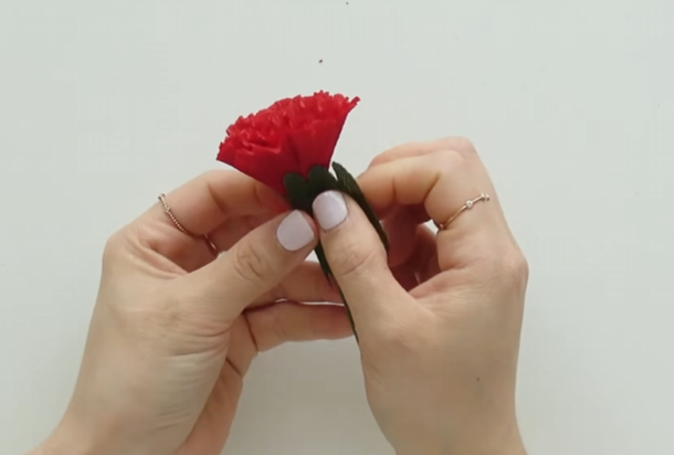 Wrapping the green sepal around the base of a handmade paper carnation