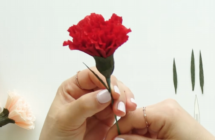 Adding a narrow crepe paper leaf along the carnation stem