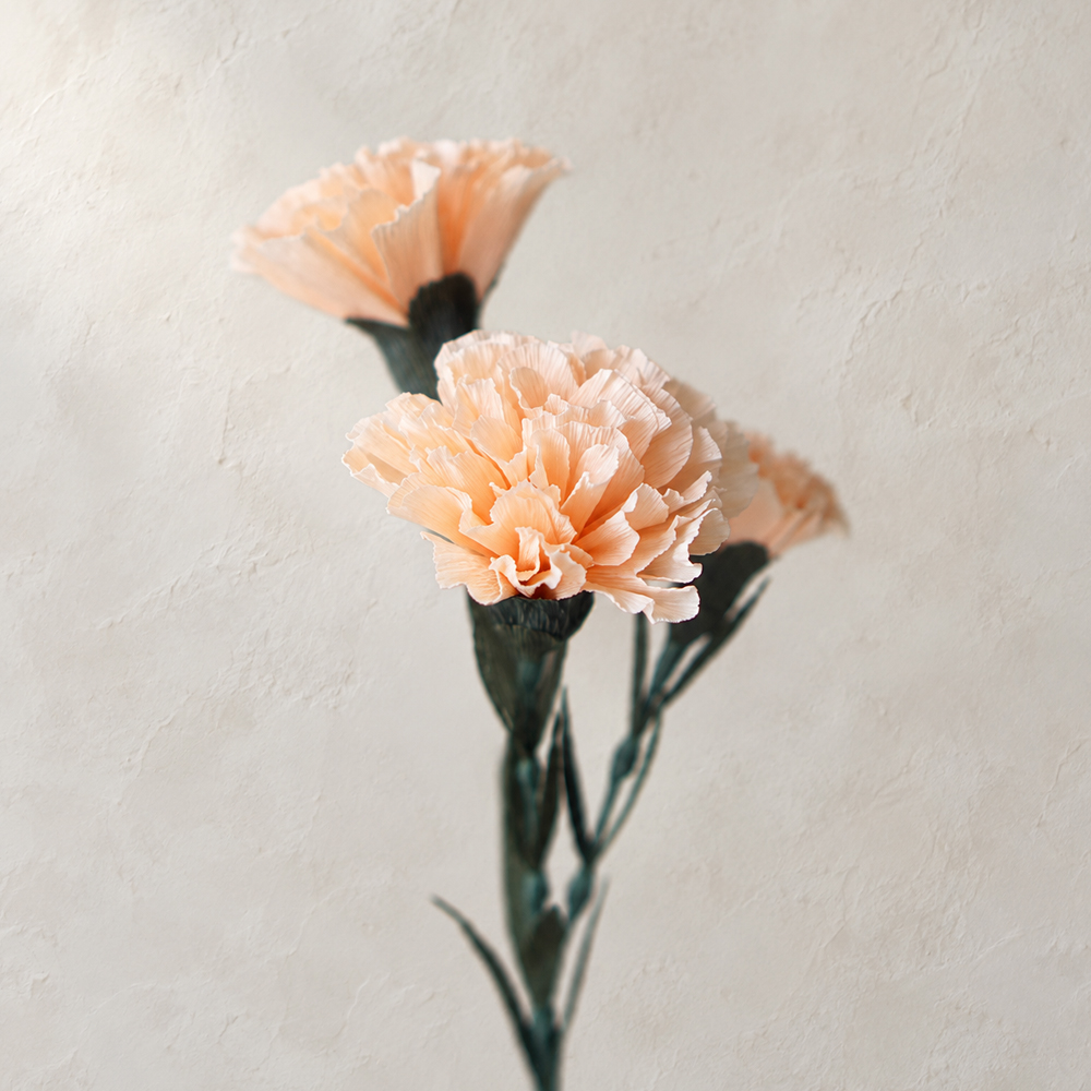 Peach crepe paper carnation flowers with realistic ruffled petals and dark green stems