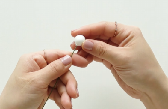 Securing a Styrofoam ball onto floral wire to create a flower bud