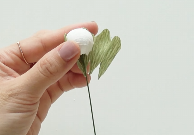Adding green sepals around a handmade white plum blossom bud