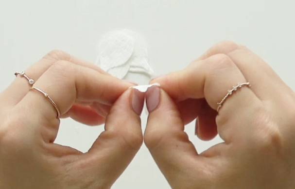 Shaping a paper flower petal by gently stretching the center with both thumbs