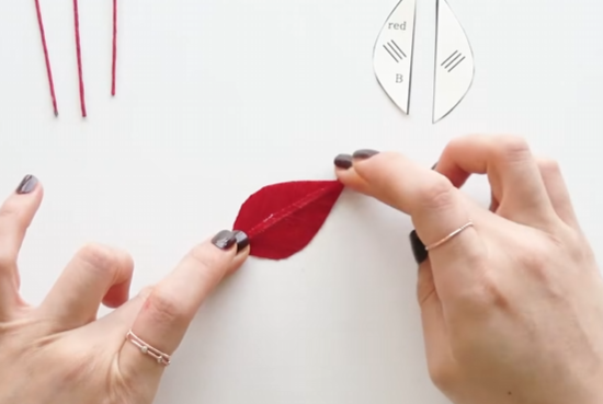 Joining two red paper petal halves around a hidden wire for a sturdy flower shape