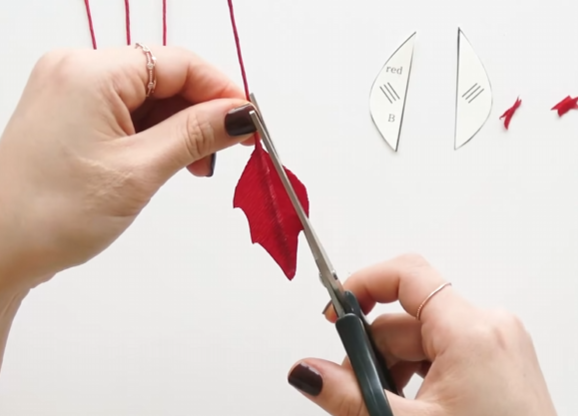 Trimming the edges of a red poinsettia petal into sharp, natural-looking points