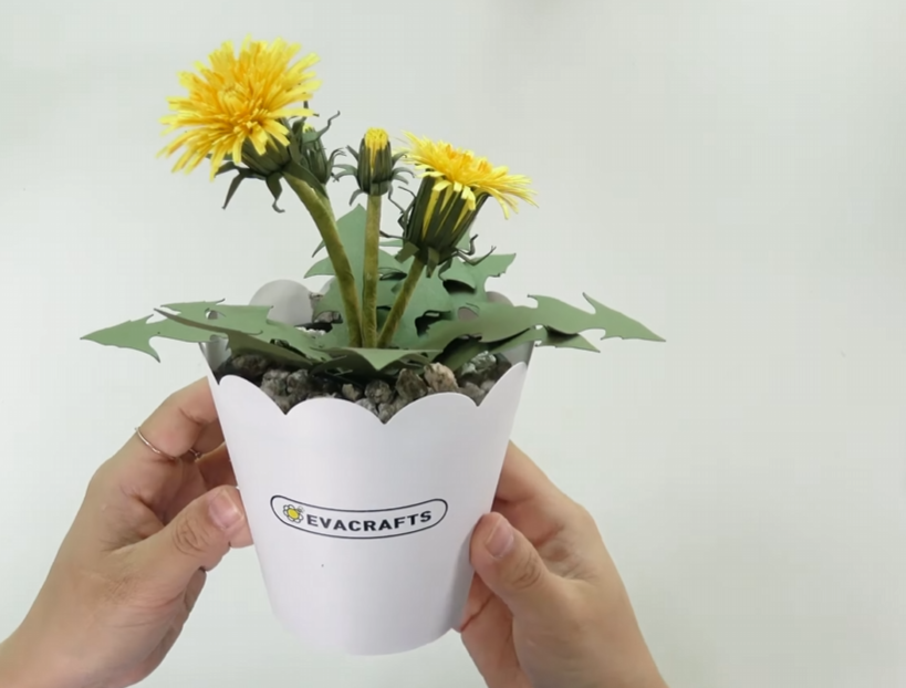 Finished paper dandelion flower pot decorated with green leaves and small pebbles