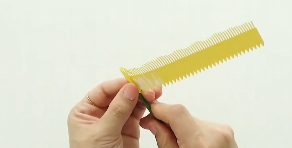 Wrapping the first yellow petal strip around a green flower stem to form the dandelion center