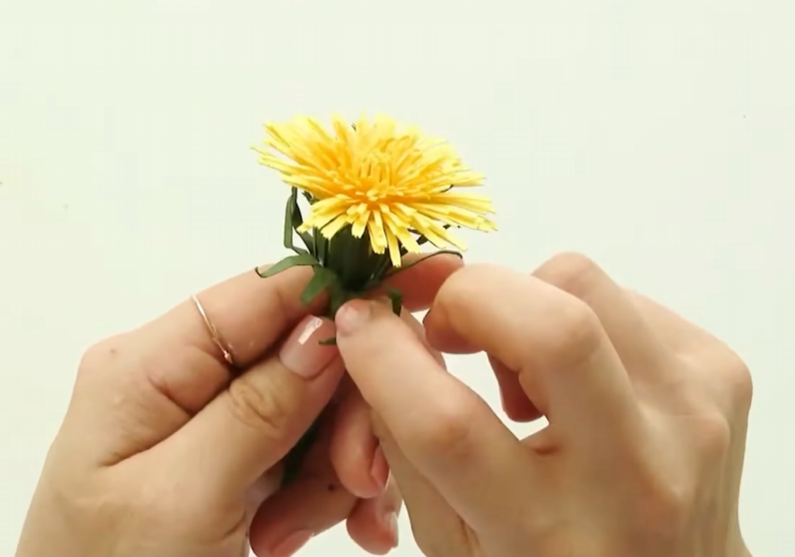 Attaching additional green sepals under the handmade dandelion flower